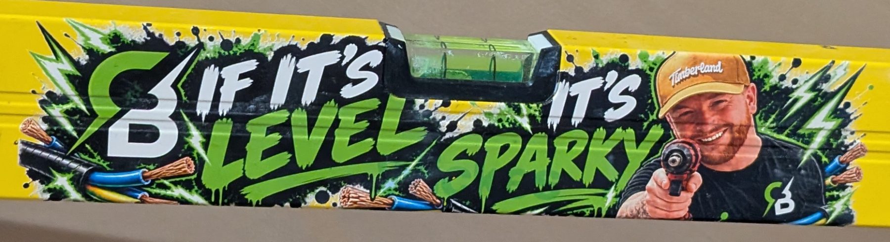 A spirit level printed in full colour with an electrician's own branding, cartoon artwork and photograph
